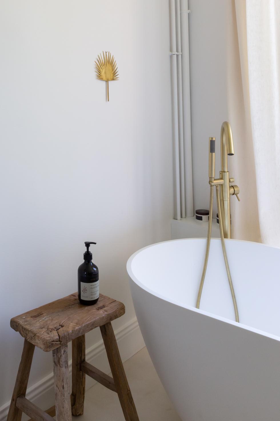 Baignoire avec robinetterie en laiton et sol en béton ciré