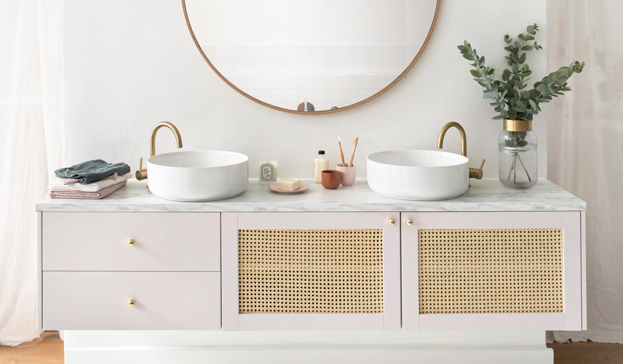 Meuble de salle de bain suspendu, avec façades en cannage Beige rosé et accessoires en laiton.